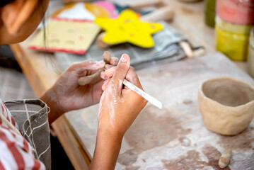 Kids making a craft of a porcelain mug from wet clay
