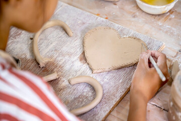 Kids making a craft of a porcelain mug from wet clay
