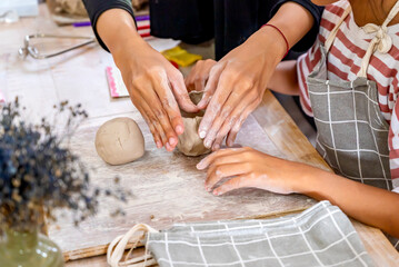 Kids making a craft of a porcelain mug from wet clay