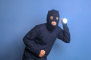 Man in black balaclava turn on the flashlight. Crime and violence concept