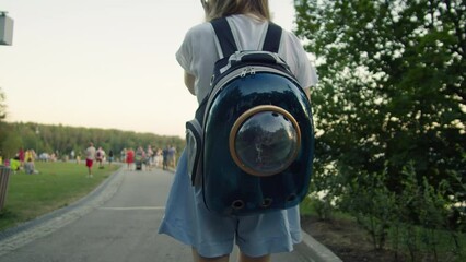 Woman owner with her little cat in the animal carrier walking in the park close-up. Kitten in pet carrier
