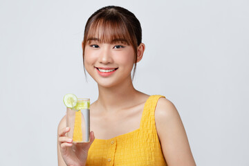 young beautiful woman standing on a white wall, relaxing with a fresh water with lemon