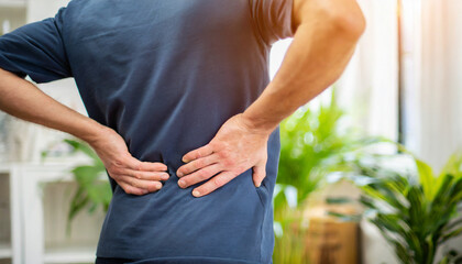 Man in discomfort, holds lower back, signifying back pain and healthcare concern
