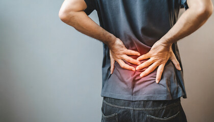 Man in discomfort, holds lower back, signifying back pain and healthcare concern - obrazy, fototapety, plakaty