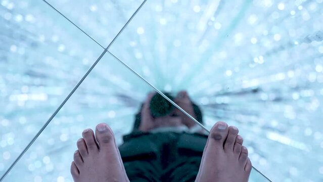 POV Of Tourist Filming Feet On Mirror Floor With Bokeh Glittering Light In Immersive Room Creating Sensory Experience. Slow Motion