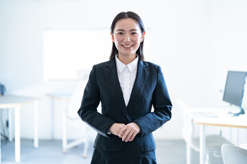 オフィスにいる若手のスーツを着た日本人女性