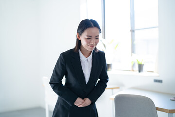オフィスにいる若手のスーツを着た日本人女性