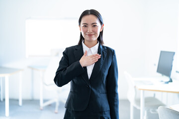 胸に手を当てるスーツを着た日本人女性