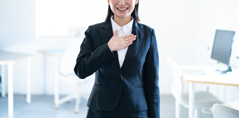 胸に手を当てるスーツを着た日本人女性