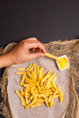 French fry into a rich dollop of creamy mustard sauce, against, textured backdrop.