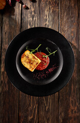 Grilled cheese with berry sauce on a black plate, viewed from above