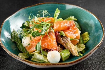 Salad with salmon, mozzarella, and avocado, served in a turquoise ceramic bowl