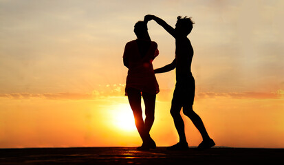 latin hispanic couple is dancing bachata salsa tango on summer beach. Sunset sky. 2 Two silhouettes...
