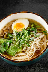 Traditional ramen with egg, greens, and mushrooms in a blue bowl