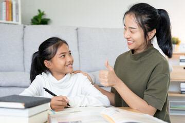 Mother teaching lesson for daughter. Asian young little girl learn at home. Do homework with kind mother help, encourage for exam.. Girl happy Homeschool. Mom advice education together.