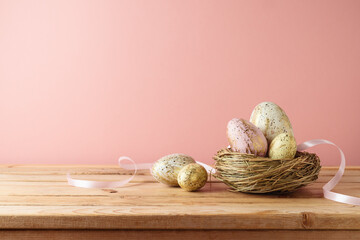 Easter holiday concept  with easter eggs iin bird nest decoration on wooden table over pink background