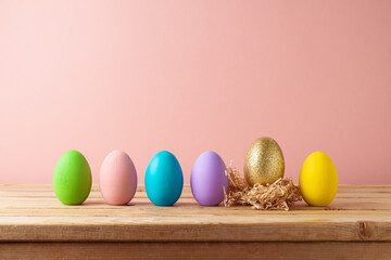 Easter holiday concept  with colorful easter eggs on wooden table over pink background