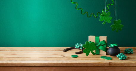 St Patrick's day concept with shamrock and gift box on wooden table over green background. Holiday...