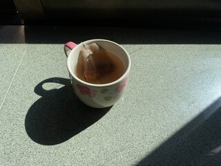 Hot tea in a glass with sunlight shining through the glass.
