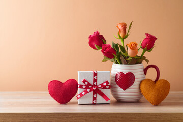 Happy Valentine's day concept with rose flowers, gift box and heart shapes on wooden table over...
