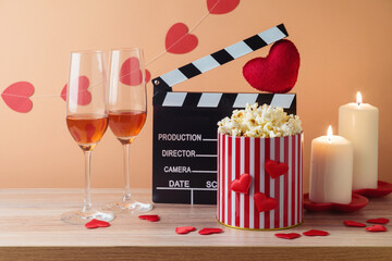 Happy Valentine's day and romantic movie concept with  movie clapper board, heart shapes, wine and popcorn on wooden table over trendy background
