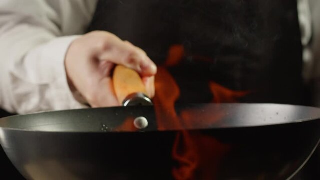 Chef cooking mushrooms on wok frying pan close up. Champignons mushroom with salt in pan. Restaurant Food concept