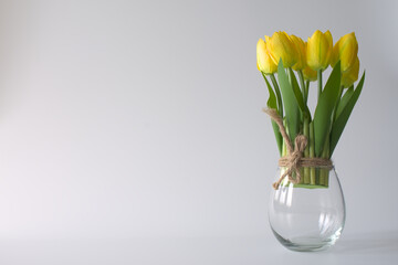 Artificial tulips flowers in a glass jar on white background.