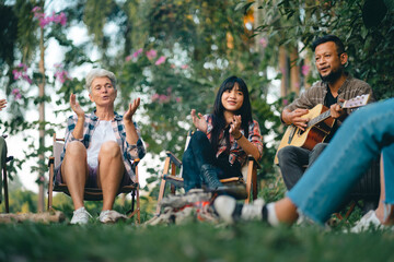 Group of man and woman friends and family singing and playing guitar during having breakfast...