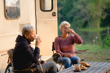 Multi-generation family sitting and eating outdoors by car, caravan holiday trip, Family vacation parents enjoy bonding camping in woods travel