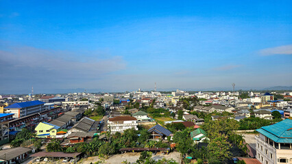 Fototapeta premium High angle shot view to the house-tops in Chumphon city is a southern of Thailand province city. Aerial view, Clear and bright day. city, landscape, village,building, school, sky, nature, clouds