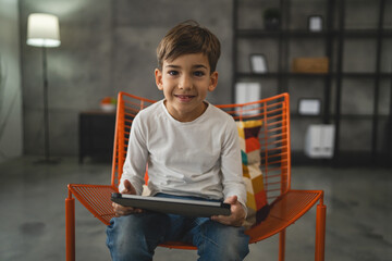 One schoolboy caucasian boy sit at home use digital tablet - Powered by Adobe