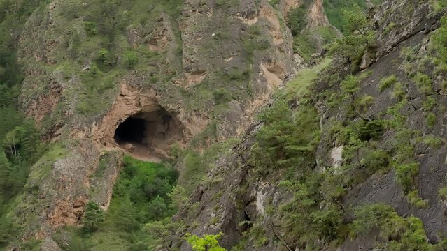 Rocky terrain with a natural tunnel. A cave in the mountains.