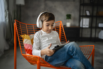 One schoolboy caucasian boy sit at home use digital tablet