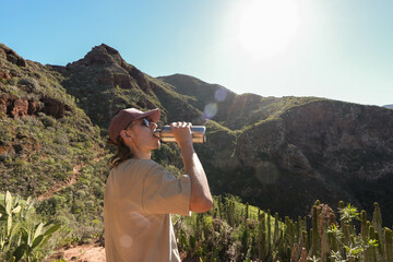 Young man thirsty Drinking Water in a brake Amidst Nature, Captured in Bright Daylight with...