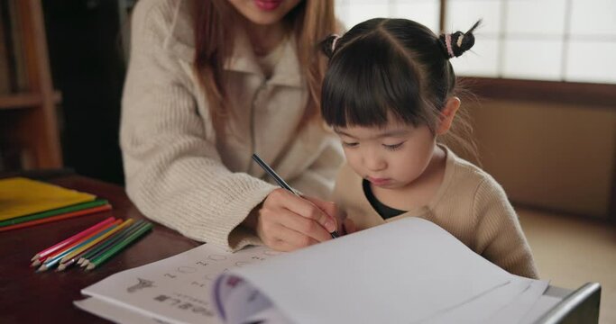 Japanese Mom, child and education with homework, writing and books for study, development and helping hand. Learning, mother and daughter with notes, pen and check progress in family house with study