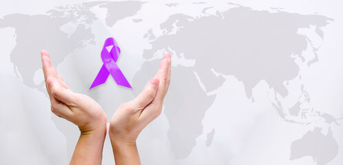 Hand hold purple ribbons for a World cancer awareness day.