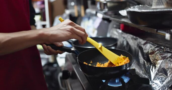 Hands, food or rice in kitchen with chef for Japanese lunch, dinner or healthy meal for nutrition. Person, omurice and preparation or cooking with wooden spoon in restaurant, cafe or small business