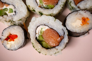 Chop sticks, mushrooms, noodle ramen, California rolls and Philadelphia rolls on a small plate on a pink background
