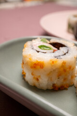 Chop sticks, mushrooms, noodle ramen, California rolls and Philadelphia rolls on a small plate on a pink background
