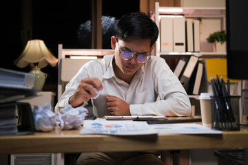 Young businessman working overtime on a desk at night..