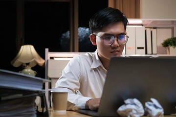 Young businessman working overtime on a desk at night..