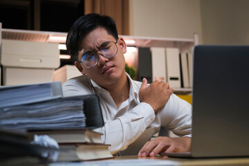 Asian businessman overtime work and feel shoulder pain in the office.
