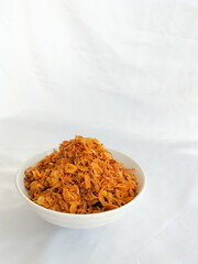 Crispy fried shallots on white bowl. Staple condiment of Southeast Asian cuisine isolated on white background. Close-up.
