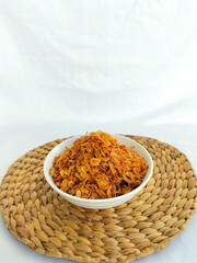 Crispy fried shallots on white bowl. Staple condiment of Southeast Asian cuisine isolated on white background. Close-up.

