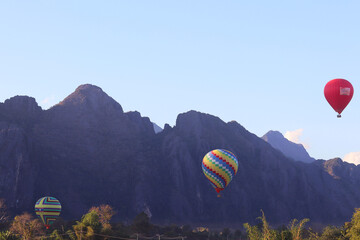 Colorful hot air balloon flying in the blue sky over the mountains