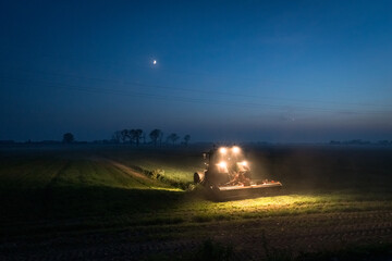 Evening with a tractor in a field with a crescent moon