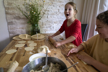 a mother with two daughters cooks at home, makes manti, steamed