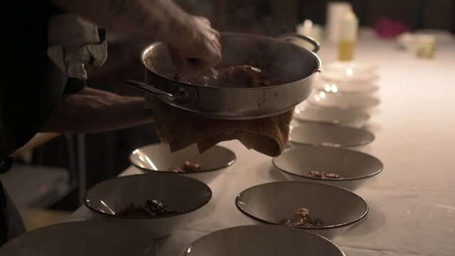 Close-up of the hands of a cook plating food for service.