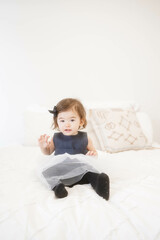 Toddler Girl in Navy Tulle Dress Sitting on a Bed