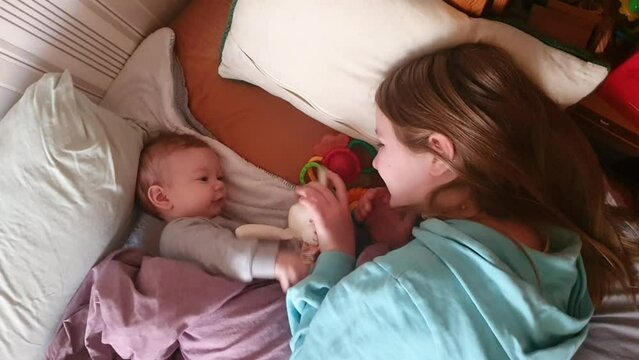 newborn baby playing with older sister